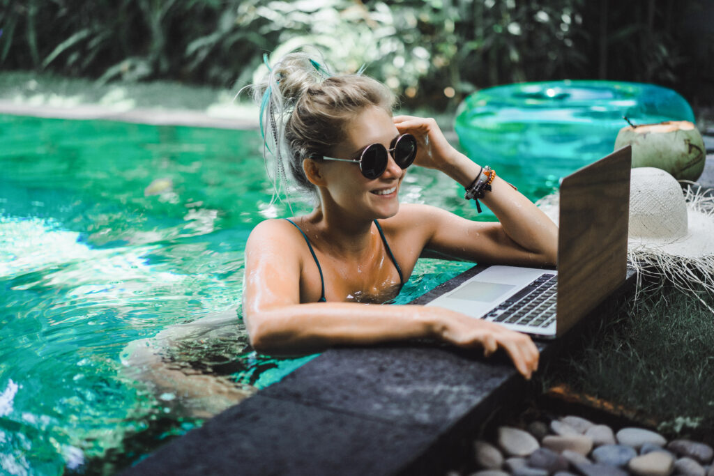 young woman working remotly with her laptop sitting in a pool