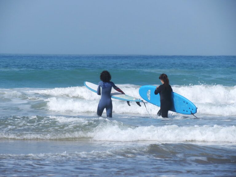 two-persons-entering-the-sea-with-surfboard